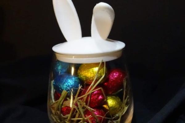 Verre avec des oreilles de lapin fourni avec des œufs en chocolat.