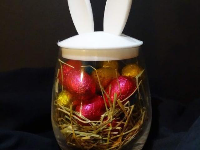 Verre avec des oreilles de lapin fourni avec des œufs en chocolat.